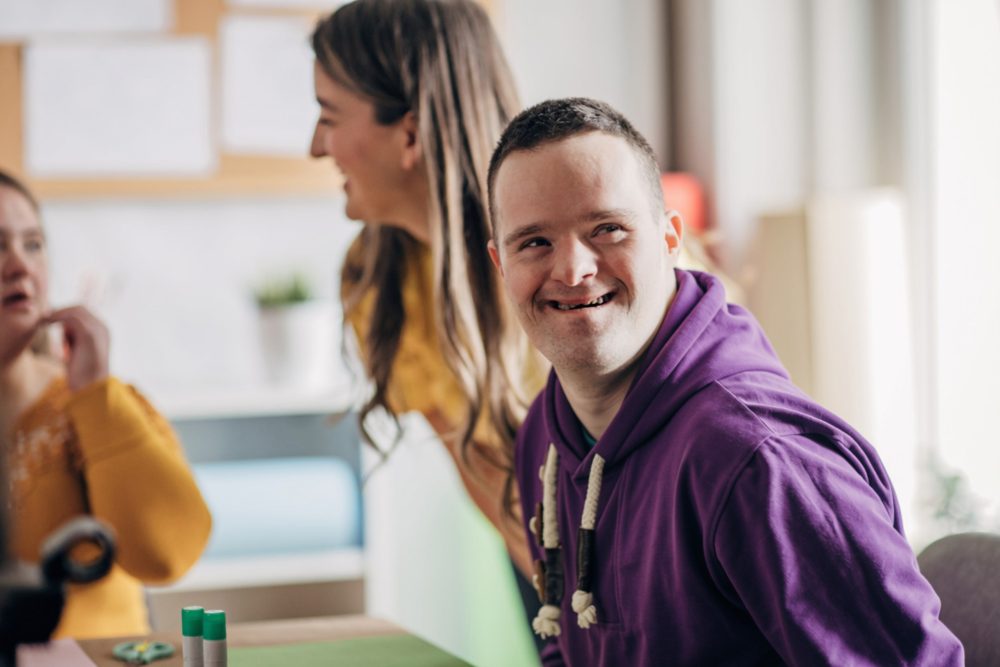 A young man laughing with others in a bright workshop